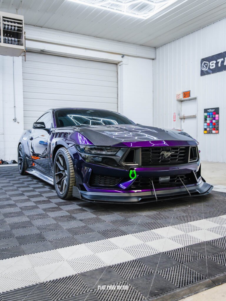 Purple wrapped Ford Mustang with aero kit, staged in the bay.