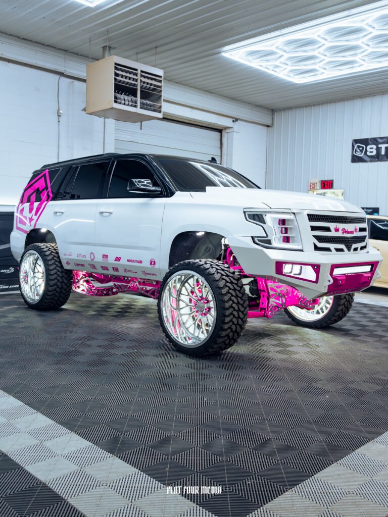 Lifted white Chevy Tahoe with pink accents and wrap decals.